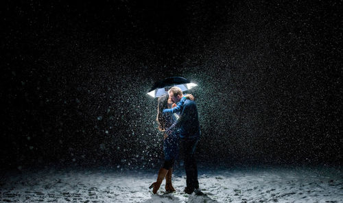 Couple standing out in the snow kissing