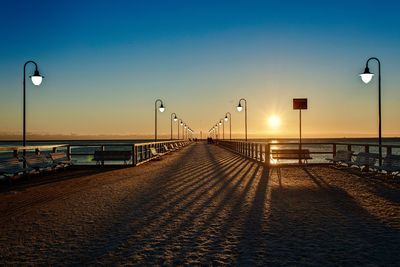 Street lights on beach against clear sky during sunset