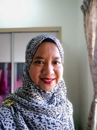 Portrait of smiling young woman wearing sunglasses at home