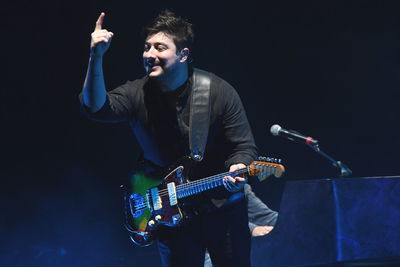 Full length of man playing guitar against black background