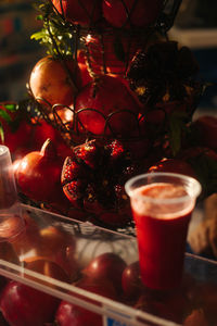 Glass full of pomegranate juice with pomegranates in the back