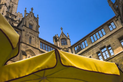 Low angle view of yellow building and parasol against sky