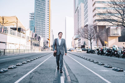 Full length of businessman walking on road against building