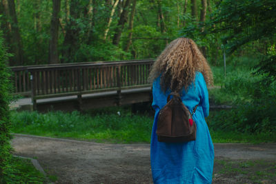 Rear view of woman standing at forest