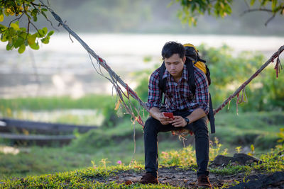 Young man looking away while sitting on land