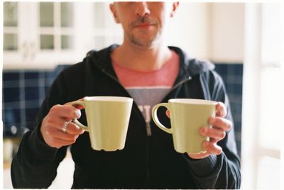 Midsection of man holding coffee cup