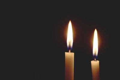 Close-up of burning candle against black background