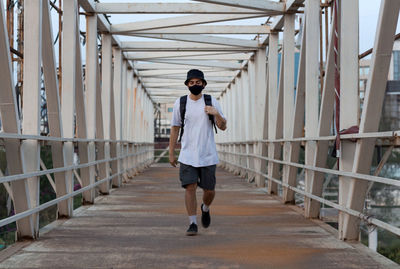 Full length of young man walking on footbridge