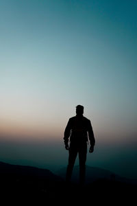 Silhouette man standing against sky during sunset