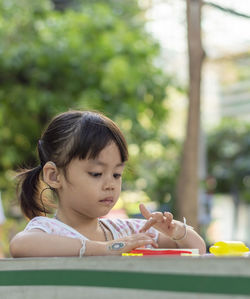 Close-up of cute girl playing with childs play clay at table outdoors
