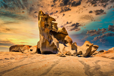 Rock formation on beach against sky during sunset