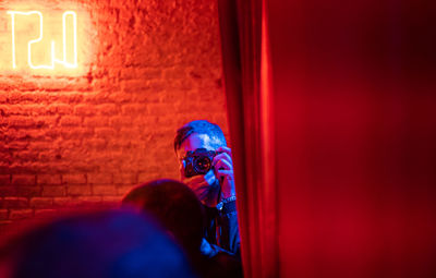 Rear view of man and woman standing against illuminated wall