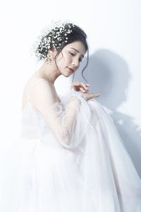 Young woman with arms raised hair against white background