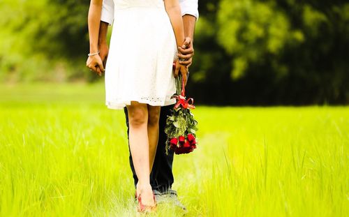 Low section of couple standing on grassy field