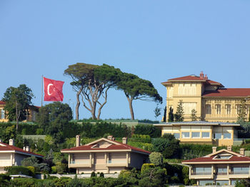 Houses by trees and buildings against clear blue sky