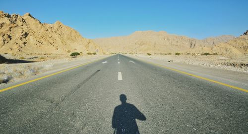 Shadow of person on road against clear sky