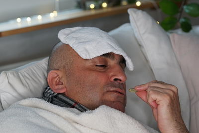 Close-up of man having pill while lying on sofa