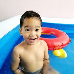 Portrait of cute boy smiling while sitting in swimming pool