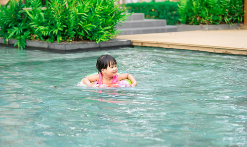 Smiling cute girl swimming in pool