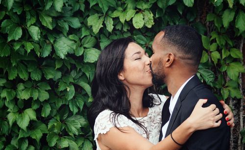 Close-up of couple kissing against plants