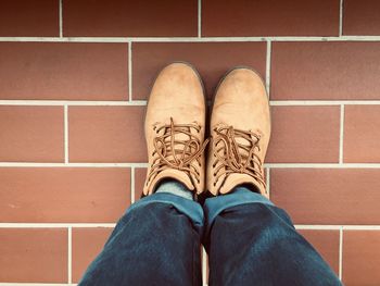 Low section of man wearing shoes while standing on tiled floor