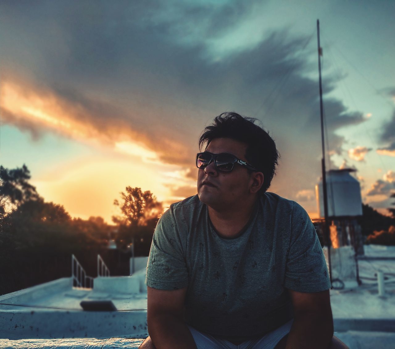 glasses, sunset, sky, cloud - sky, one person, sunglasses, fashion, real people, lifestyles, focus on foreground, front view, leisure activity, nature, young adult, waist up, casual clothing, young men, portrait, men, outdoors, contemplation