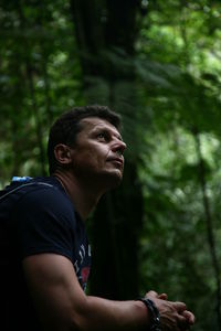 Side view of mid adult man looking up in forest