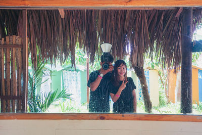 Man and woman with camera reflecting on mirror while photographing