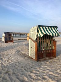 Hooded chairs on beach against sky