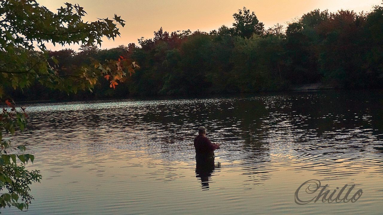 water, tree, sunset, silhouette, tranquil scene, tranquility, scenics, reflection, beauty in nature, nature, lake, sky, one person, idyllic, waterfront, orange color, rippled, outdoors, growth, non-urban scene