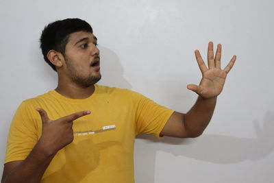 Portrait of young man standing against wall