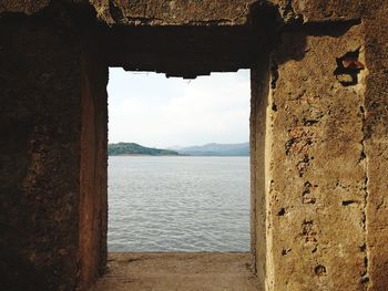 Sea against sky seen through window