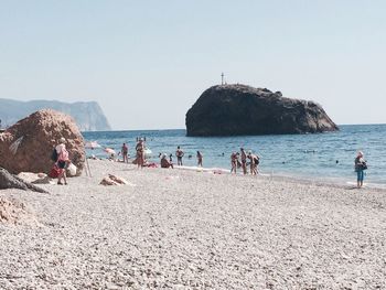 Group of people on beach against clear sky