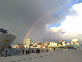 Rainbow over buildings in city against sky