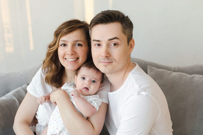 Portrait of smiling parents with daughter at home