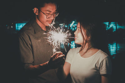 Young man with woman standing at night