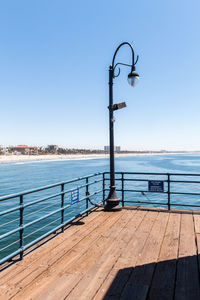 Jetty leading to calm sea against clear blue sky