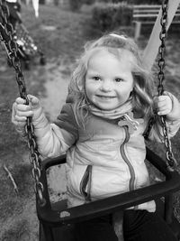 Smiling girl looking away while swinging at playground