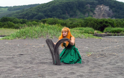 Woman playing with sand at beach against sky