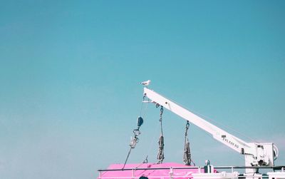 Low angle view of crane against clear blue sky