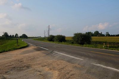 Road amidst field against sky