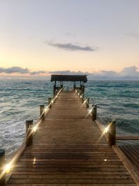 Pier over sea against sky during sunset