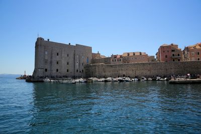 View of buildings by sea against clear sky
