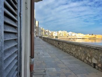 Footpath by buildings against sky