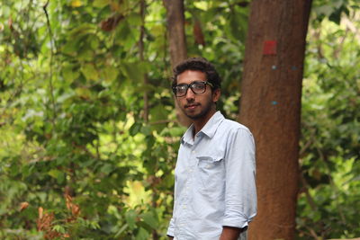 Portrait of man standing against trees in forest