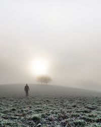 Man on snowy field against sky during winter