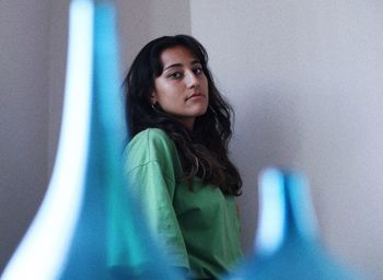 Portrait of young woman looking down behind a vase