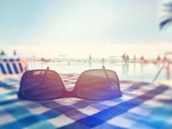 Close-up of sunglasses at swimming pool against sky