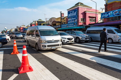 Vehicles on road against sky in city