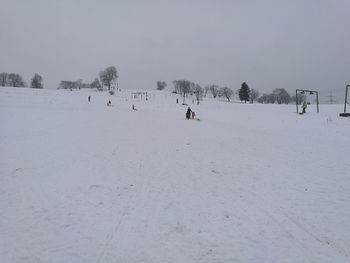 People in snow against clear sky